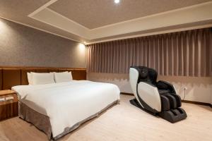 um quarto de hotel com uma cama e uma cadeira em The Cloud Hotel em Zhubei