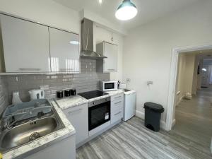 a white kitchen with a sink and a microwave at Rooms Near Me - Apartment 2, Smart Tv, Free Parking in Halesowen