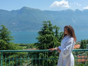 a woman standing on a balcony looking at the mountains at Hotel San Pietro in Limone sul Garda