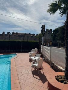 een patio met een tafel en stoelen naast een zwembad bij Hotel Le Mura in Lazise