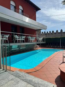 a swimming pool in front of a building with tables and chairs at Hotel Le Mura in Lazise