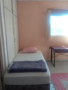 a small bed in a room with a window at Agartha Hostel in Boquete