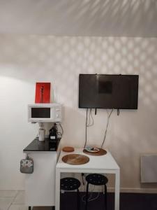 een keuken met een witte tafel en een tv aan de muur bij Studio Indépendant avec terrasse proche Paris in Épinay-sur-Seine +15 foto's