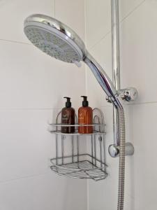 a shower head with two bottles on a shelf in a bathroom at Briar Cottage Guest Suite in Norwood Green, Halifax in Halifax