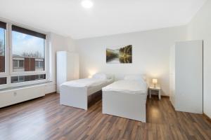 2 Betten in einem weißen Zimmer mit Fenster in der Unterkunft Schickes Apartment mit Balkon in Dorsten