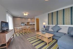 East Altitude في بورنموث: غرفة معيشة مع أريكة زرقاء وطاولة