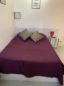 a bedroom with a purple bed with pillows at Malocco in Pontcarré