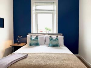 a bedroom with blue walls and a bed with two pillows at Modern And Vibrantly Designed Apartment in Motherwell