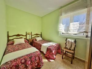 a bedroom with two beds and a window and a chair at La Esteluca - 6805 in Noja