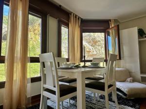 comedor con mesa, sillas y ventanas en La Sirenuca, en Santoña