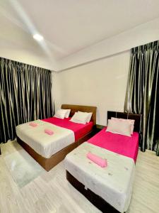 a bedroom with two beds with pink sheets at Sutera Luxurious Loft 1 in Kota Kinabalu