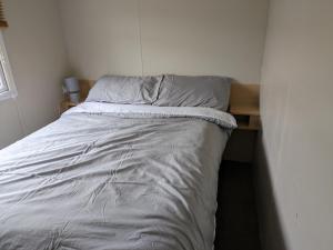 een bed in een kleine kamer met een nachtrok bij The Hidden Gem in Galloway Forrest in Balminnoch