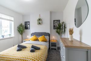 a bedroom with a bed with yellow pillows and a mirror at Open Mind Property - Luxury 3 Beds & Free Parking in Portsmouth
