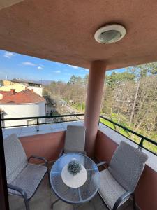 una mesa y sillas en un balcón con vistas en Apartmani Central 12 & Free parking, en Vrnjačka Banja