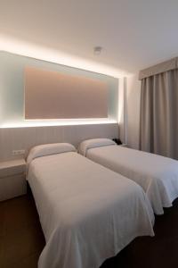 two beds in a hotel room with white sheets at Hotel Alkazar in Valencia