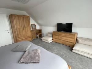 een slaapkamer met een bed en een tv en een bank bij Lancelots Breathtaking views in Tintagel