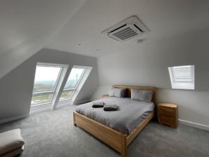 een slaapkamer met een bed en 2 ramen bij Lancelots Breathtaking views in Tintagel