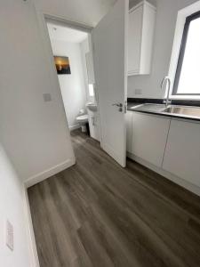 a kitchen with white cabinets and a wooden floor at Excalibur 3 Bed sleeps 7 in Tintagel