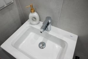 a white sink with a faucet and a bottle of soap at Batorego 18 White Prywatne mieszkanie 300m od metra Pole Mokotowskie i SGH in Warsaw