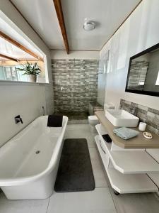 a white bathroom with a tub and a sink at Blue Bay Studio Bayview in Cape Town