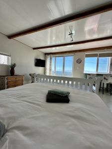 a large white bed in a room with windows at Blue Bay Studio Bayview in Cape Town