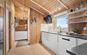a kitchen with white cabinets and wood walls at Stunning Home In Sjølund With Kitchen in Sjølund +12 photos