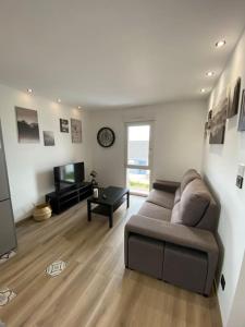 a living room with a couch and a television at Appartement climatisé in Charmes