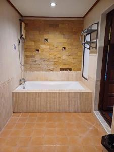 a large bath tub in a room with a stone wall at Orchid Home in Ko Tao