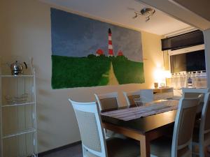 Oldenswort的住宿－Ferienwohnung Leuchtturm - b51002，一间配有桌子的用餐室和墙上绘有灯塔