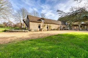 una gran casa de piedra con un patio de césped en Le Montoir en Faverolles
