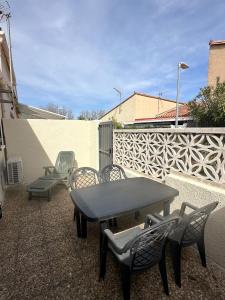 eine Terrasse mit Tisch und Stühlen und einem Zaun in der Unterkunft Maisonnette bord de Lagune et Plage St Cyprien in Saint-Cyprien