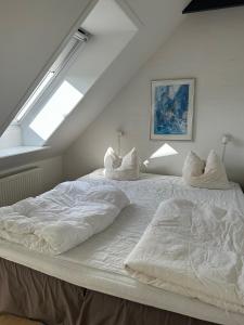 a large white bed in a room with a window at Tversted Strandpark in Bindslev