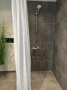 eine Dusche mit einem weißen Duschvorhang im Bad in der Unterkunft Tversted Strandpark in Bindslev