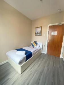 1 dormitorio con 1 cama grande y puerta de madera en Park Crescent Hotel, en Mánchester