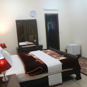 sypialnia z łóżkiem i zegarem na ścianie w obiekcie The Royal Family Couples Guest House w mieście Lahaur
