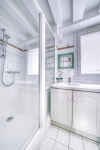uma casa de banho branca com um chuveiro e um lavatório. em 2066 - Duplex in Saint-Germain Olympic Games 2024 em Paris