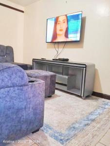 ein Wohnzimmer mit einem Sofa und einem TV in der Unterkunft Airbnb Buru Buru in Nairobi
