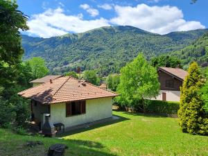 une petite maison dans une cour avec des montagnes en arrière-plan dans l'établissement Villetta singola con giardino Cottage Ghisallo zona Bellagio, à Magreglio