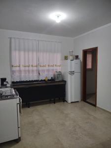 une cuisine avec un réfrigérateur blanc et une fenêtre dans l'établissement Aconchego Cuesta de Botucatu Ninho verde 2, à Pardinho
