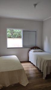 2 camas en una habitación con ventana en Aconchego Cuesta de Botucatu Ninho verde 2, en Pardinho