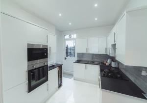 a large kitchen with white cabinets and black appliances at One bedroom flat in Harrow. in Harrow