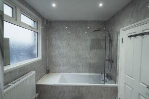 a bathroom with a bath tub and a window at One bedroom flat in Harrow. in Harrow