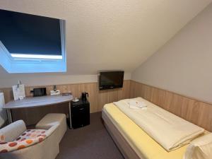 Habitación con cama, TV y silla. en Hotel am Steinertsee - Kassel-Ost, en Kaufungen