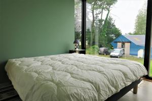 ein großes Bett in einem Schlafzimmer mit einem großen Fenster in der Unterkunft Maison de plain-pied avec WIFI, jardin, terrasse à PLEUMEUR - BODOU REF-457 in Pleumeur-Bodou