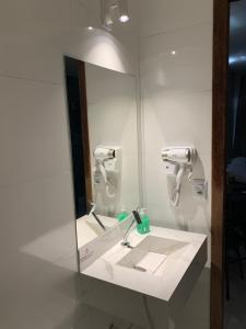 a bathroom with a mirror and a white sink at Hotel Oásis in Brasilia
