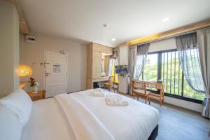 a bedroom with a large white bed and a large window at The Wood Pattani Hotel in Ban Ru Sa Mi Lae