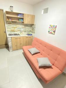 un sofá naranja en una habitación con cocina en 23 COMODO APARTAMENTO CON BALCON EN LAURELES ESTADiO, en Medellín