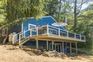 a blue house with a deck and an umbrella at Waterfront Sun-Drenched Hermit Lake Retreat! in Sanbornton