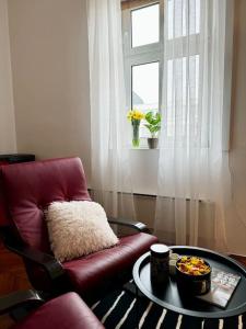 a living room with a red chair and a table at Downtown Delight: Chic Oasis in Zagreb