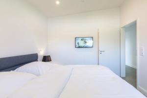 a white bedroom with a large white bed and a mirror at Georgs Huis in Neukirchen